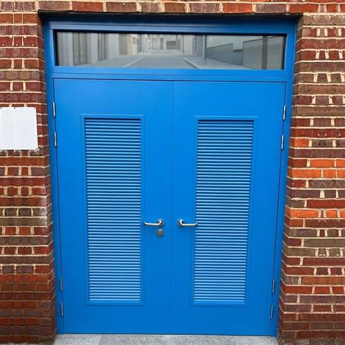 Close-up details of a robust industrial steel security door showing reinforced locking mechanism and heavy-duty hinges in a warehouse.