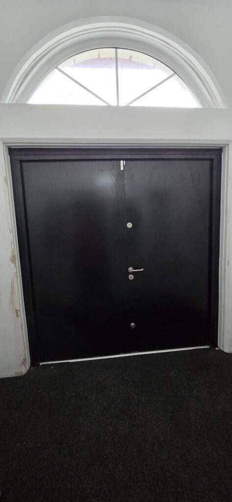 Internal view of steel double doors beneath a semicircular fanlight