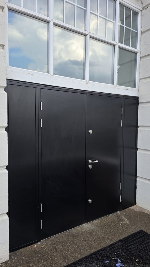 Steel double doorset with solid infill side panels below multi-pane glazing