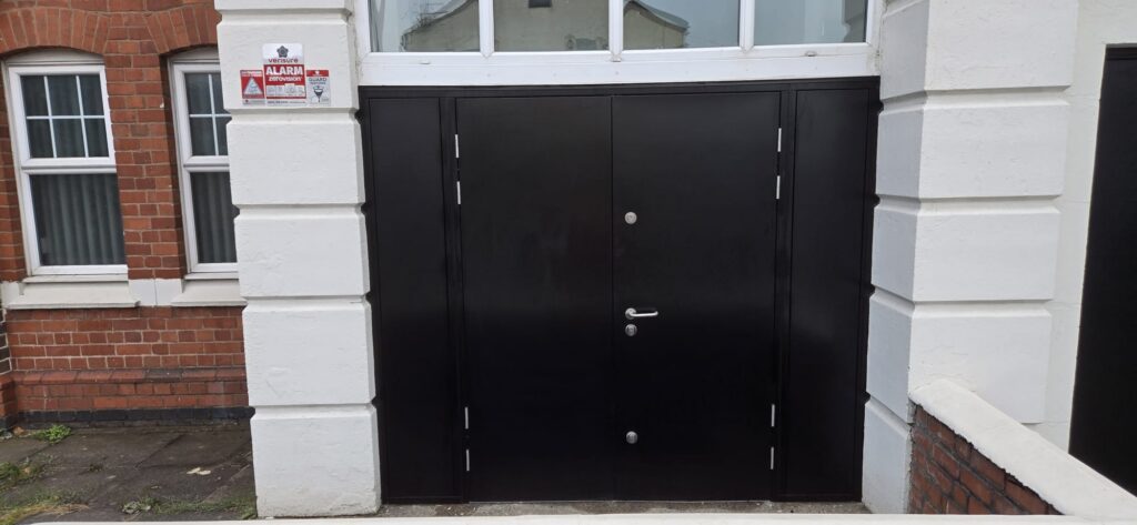 Steel security doorset with solid side panels and original glazing retained above, church in Coventry